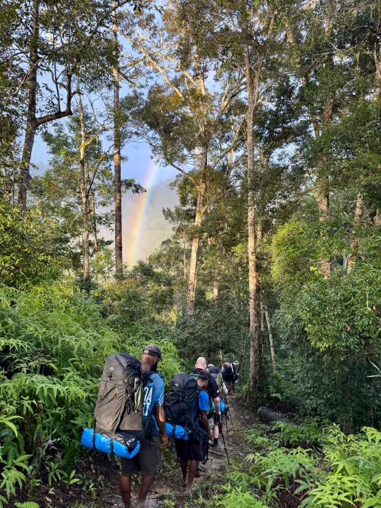 Team trekking the Kokoda Track toward a rainbow